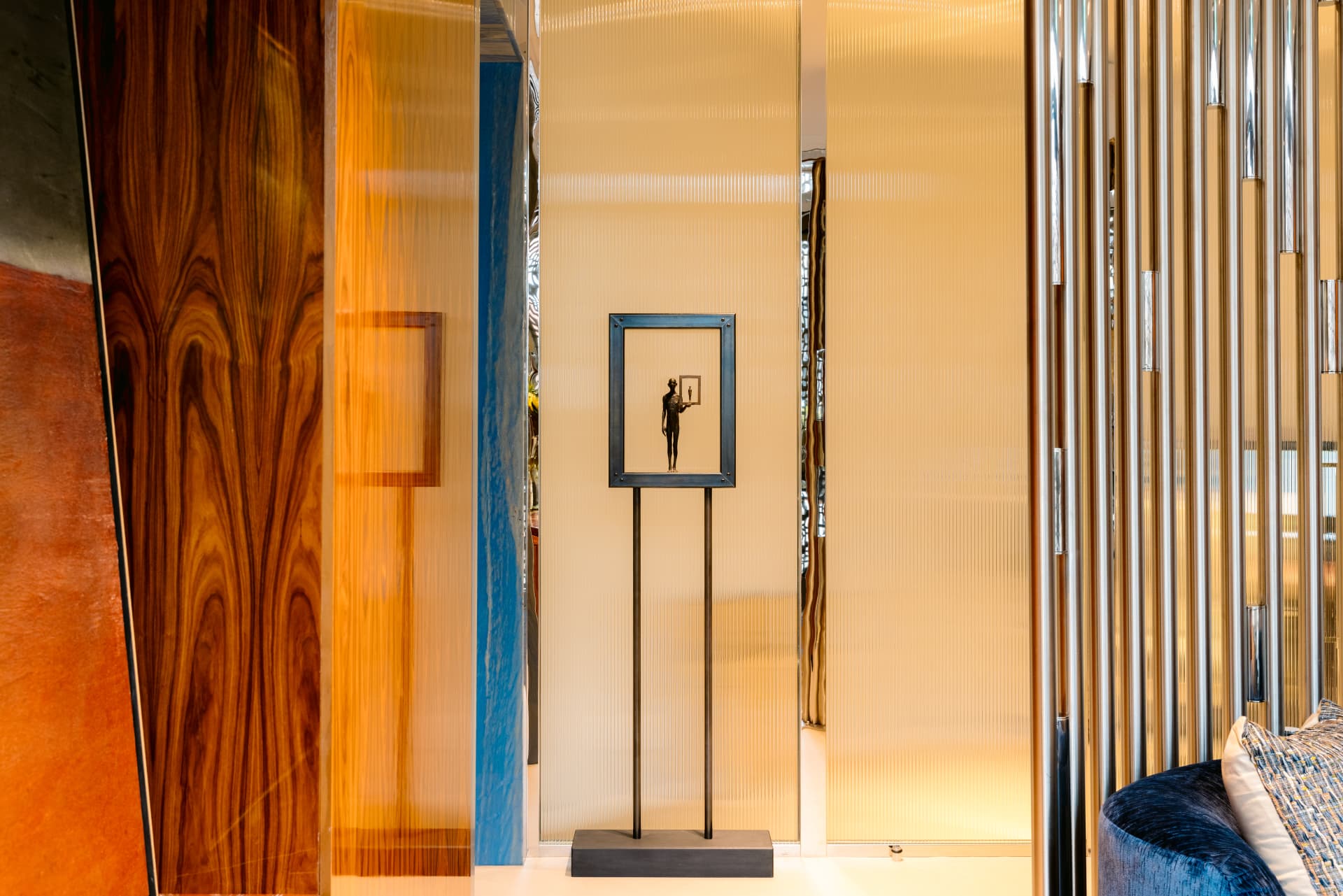 A bronze figure holding a small framed picture, displayed on a stand against fluted glass in the Globacor office