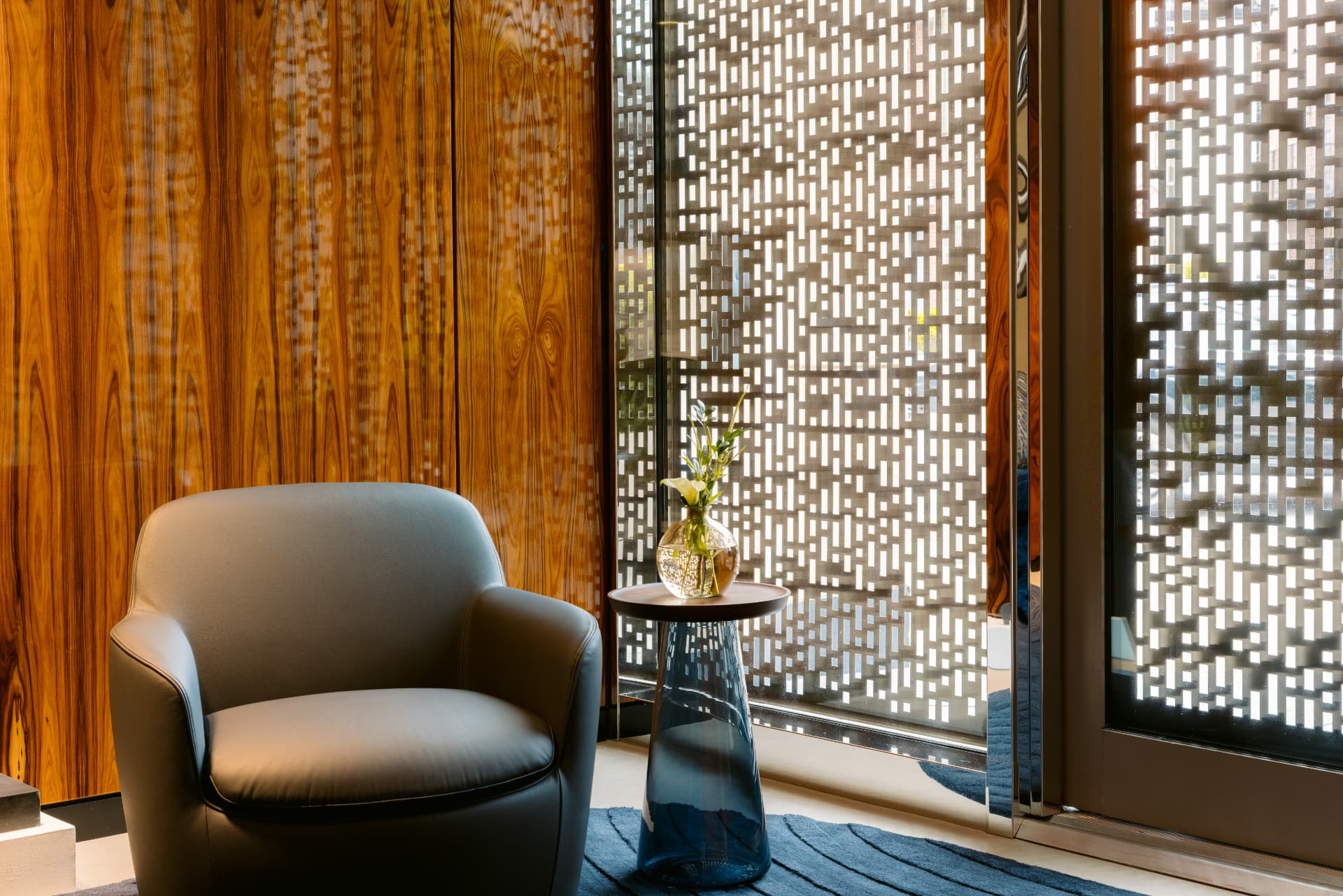 A leather armchair in the Globacor Partners office beside a walnut wall and a luminous privacy screen
